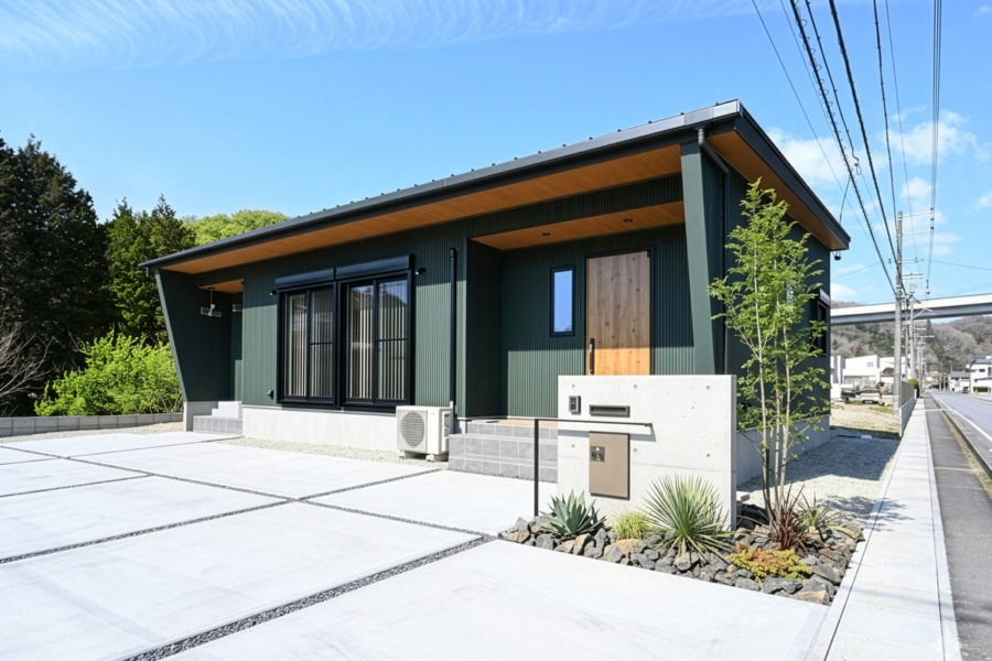 木製の玄関ドア、大きな掃き出しドア、平らな張り出し屋根を備えたモダンな平屋。外壁にカーキ・ダークグリーンのガルバリウムを使用したメンズライクでかっこいい外観。