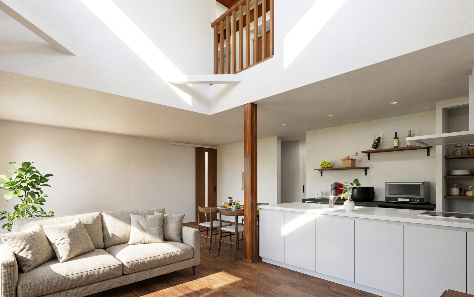 Bright open-plan living space with a beige sectional sofa, potted plant, and white kitchen island under a two-story ceiling with wooden rail.